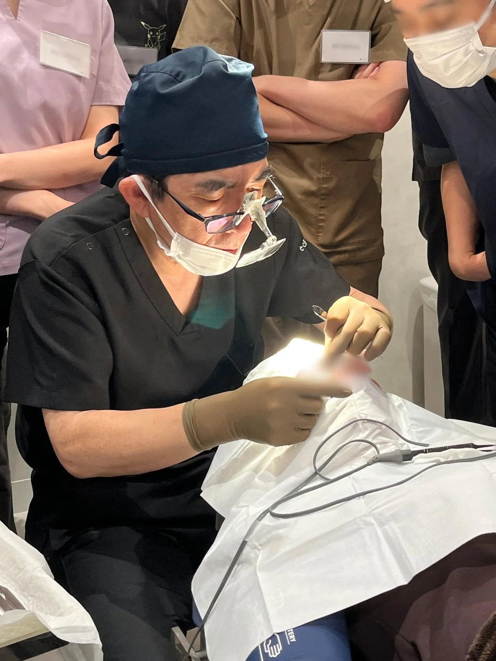 医師がルーペと手袋を使い医療処置を行っている様子