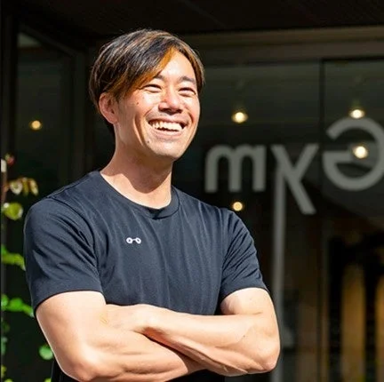 屋外で腕を組み、明るく笑うアジア人男性のポートレート