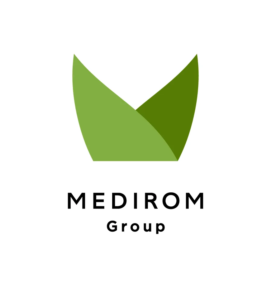 「MEDIROM Group」のロゴマークです。上部には2枚の異なる緑色の葉のような、または抽象的なV字型の図形が配置されており、その下に「MEDIROM Group」の文字が書かれています。