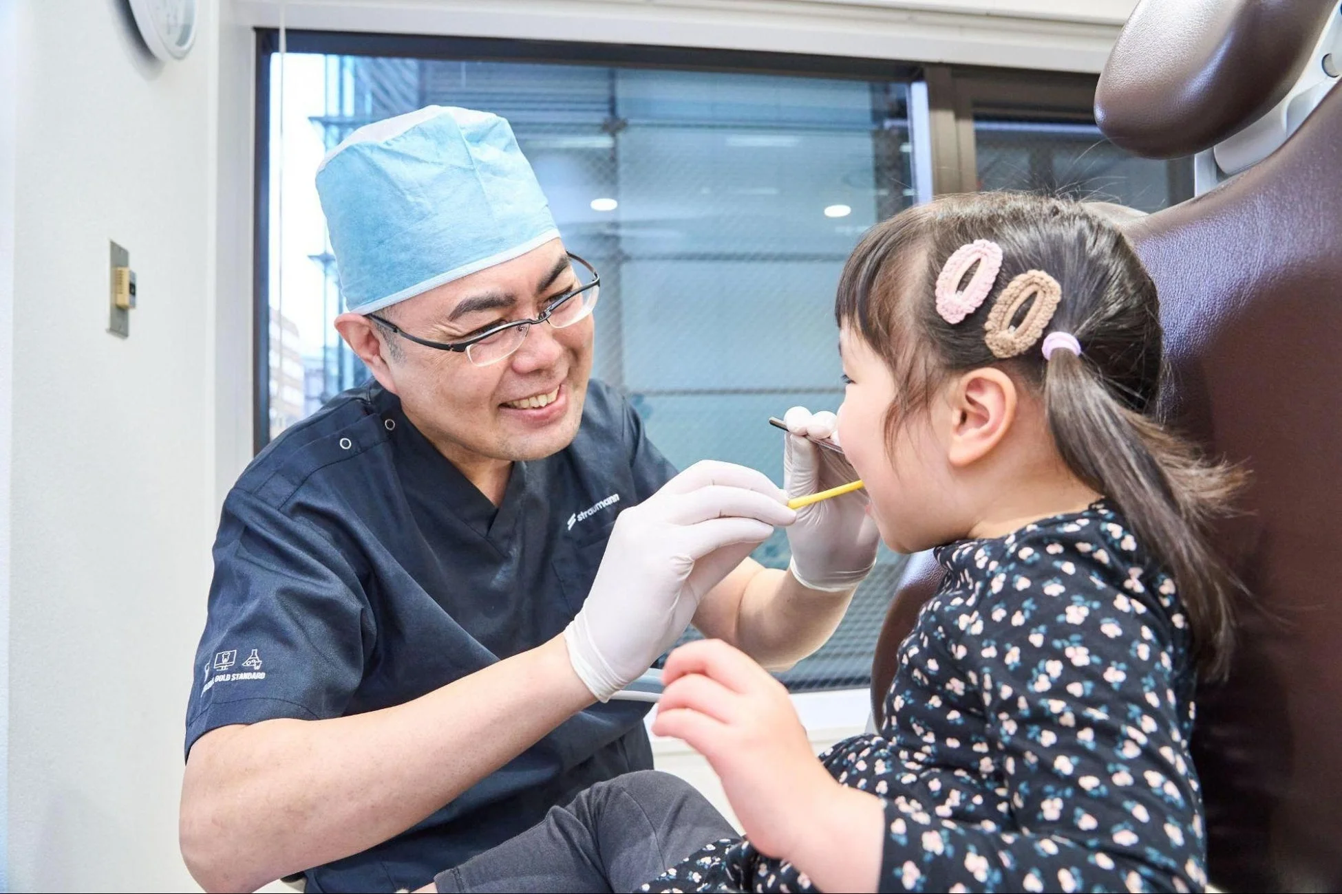 歯科医が小さな女の子の歯を診察している様子