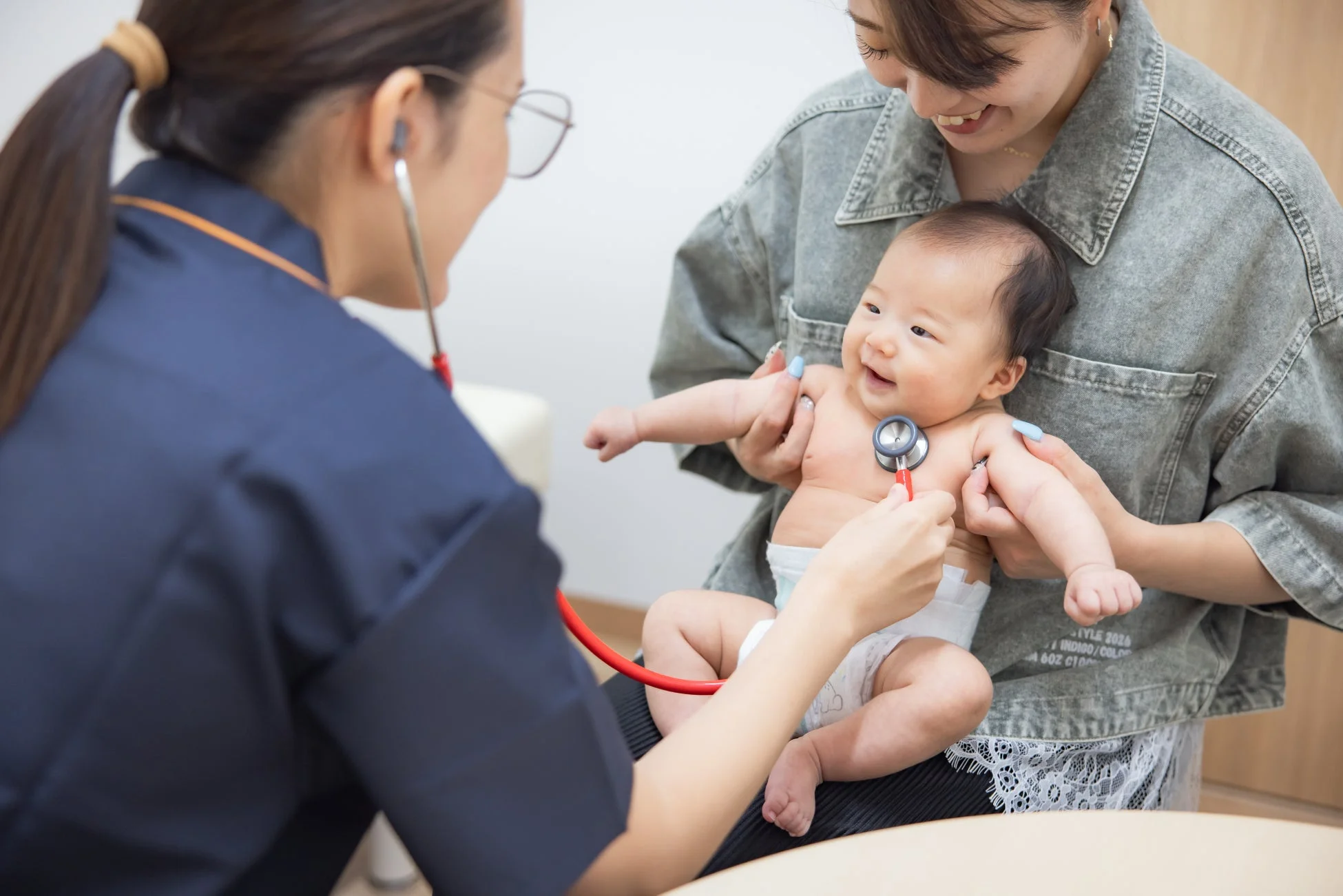 母親に抱かれた赤ちゃんが、医療従事者による健康診断を受けている様子