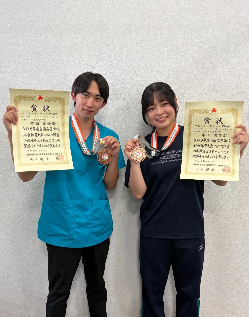 令和8年度全国高等学校総合体育大会ウエイトリフティング競技で、男子81kg級と女子63kg級でそれぞれ3位に入賞した高校生2人が、賞状とメダルを誇らしげに掲げています。