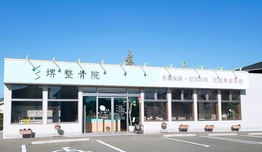 青い空の下、白いモダンな外観の「琲 整骨院」です。