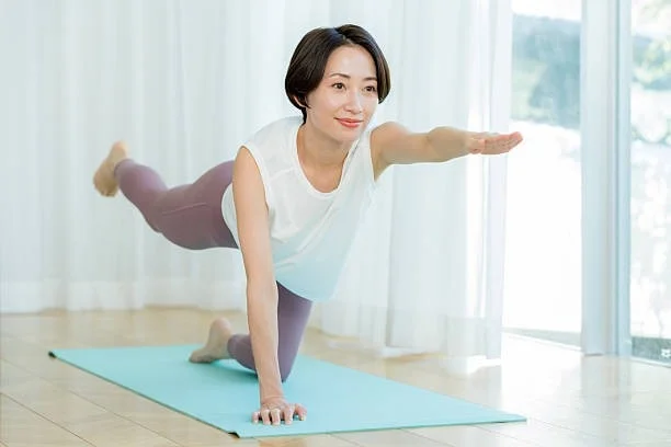 女性がヨガマットの上でバランスを取りながらエクササイズをしている様子