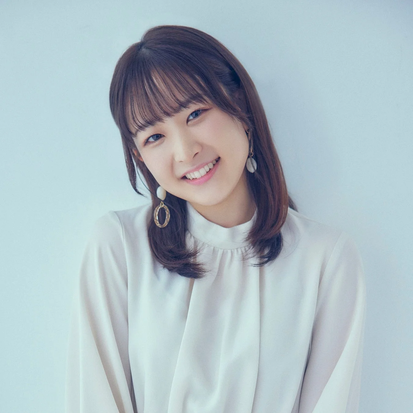 白いブラウスを着た若い女性がカメラに向かって優しく微笑んでいるポートレート写真